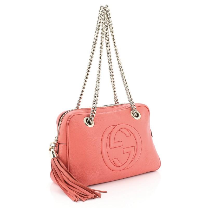 This Gucci Soho Chain Zip Shoulder Bag Leather Small, crafted from pink leather, features dual chain link straps, interlocking Gucci logo stitched in front, tassel zip pull, and gold-tone hardware. Its zip closure opens to a neutral fabric interior