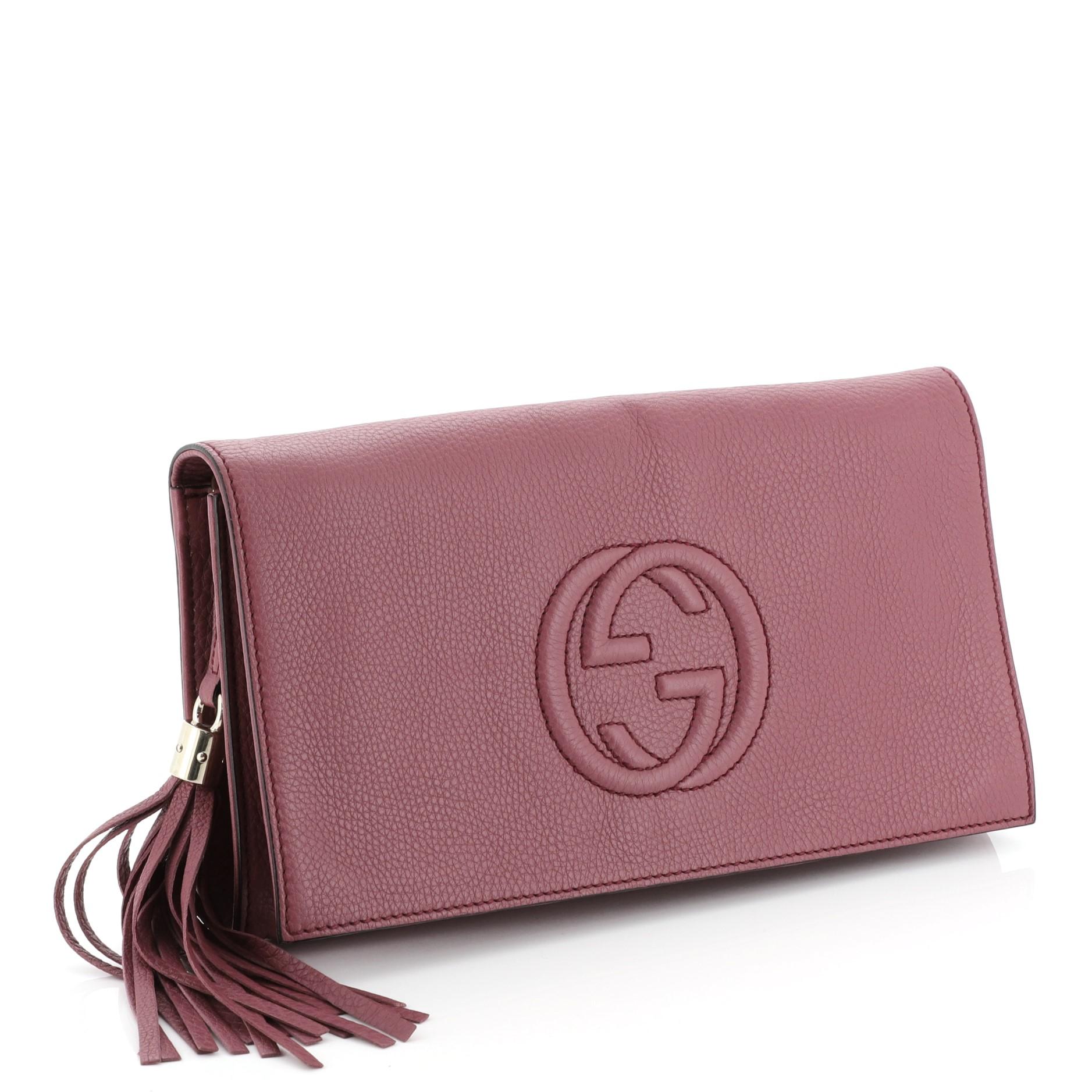 This Gucci Soho Clutch Leather, crafted from purple leather, features leather tassels, embossed interlocking GG logo, and gold-tone hardware. Its hidden magnetic snap closure opens to a neutral fabric interior with zip and slip pockets. 

Estimated