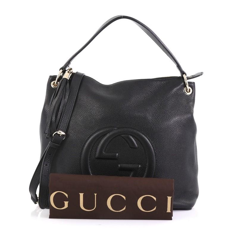This Gucci Soho Convertible Hobo Leather Large, crafted from black leather, features interlocking GG logo stitched at the front, single looped shoulder strap, leather tassel zipper pull, and gold-tone hardware. Its zip closure opens to a beige