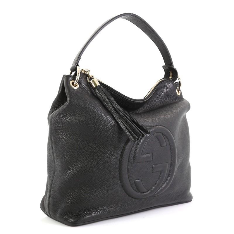 This Gucci Soho Convertible Hobo Leather Large, crafted from black leather, features interlocking GG logo stitched at the front, single looped shoulder strap, leather tassel zipper pull, and gold-tone hardware. Its zip closure opens to a neutral