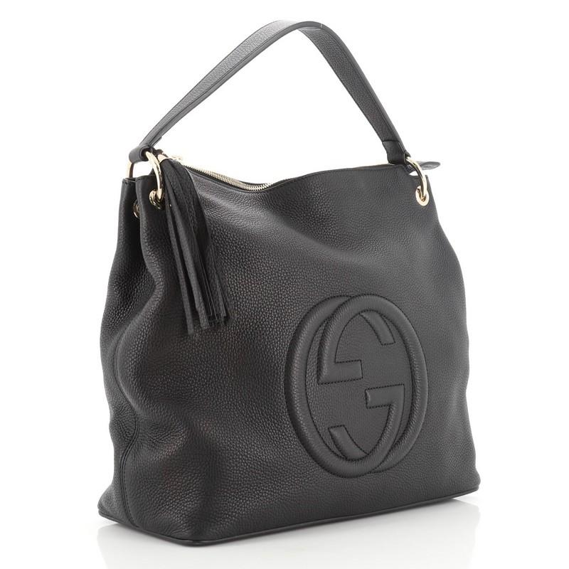 This Gucci Soho Convertible Hobo Leather Large, crafted from black leather, features interlocking GG logo stitched at the front, single looped shoulder strap, leather tassel zipper pull, and gold-tone hardware. Its zip closure opens to a neutral