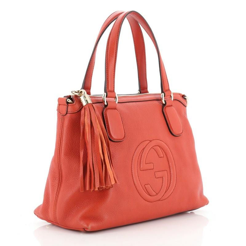 This Gucci Soho Convertible Soft Top Handle Bag Leather, crafted from orange leather, features dual flat handles, interlocking GG logo stitched at the front, leather tassel zip pull, protective base studs, and gold-tone hardware. Its zip closure