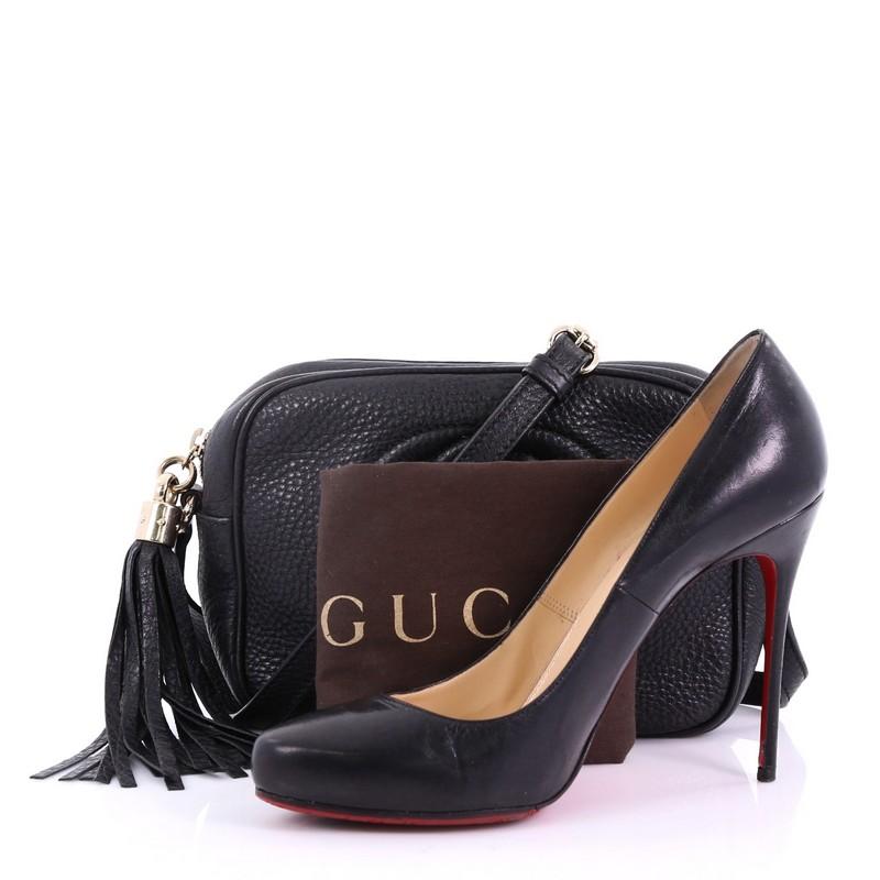 This Gucci Soho Disco Crossbody Bag Leather Small, crafted in black leather, features an adjustable leather strap and gold-tone hardware. Its zip closure opens to a beige fabric interior with slip pockets. **Note: Shoe photographed is used as a