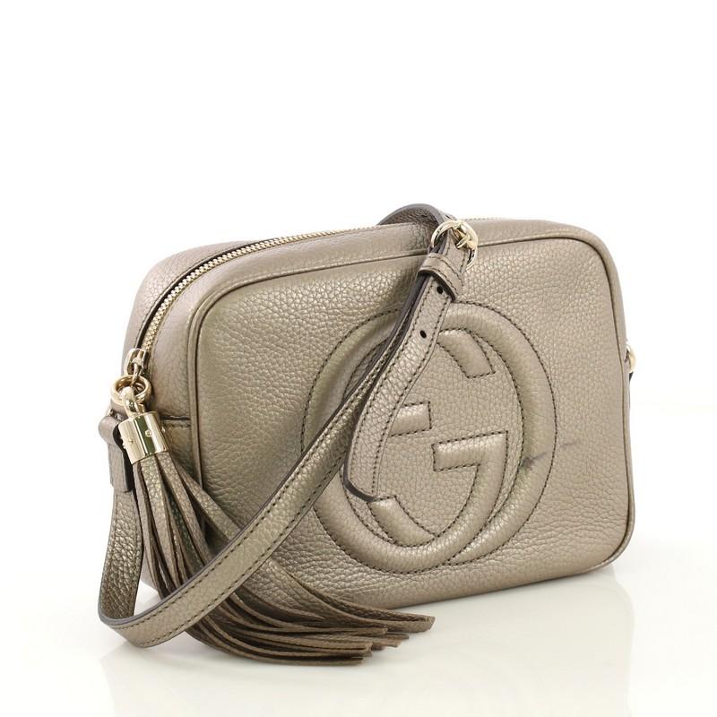 This Gucci Soho Disco Crossbody Bag Leather Small, crafted in metallic gold leather, features an adjustable leather strap, tassel zip pull, and gold-tone hardware. Its zip closure opens to a beige fabric interior with slip pockets. 

Estimated