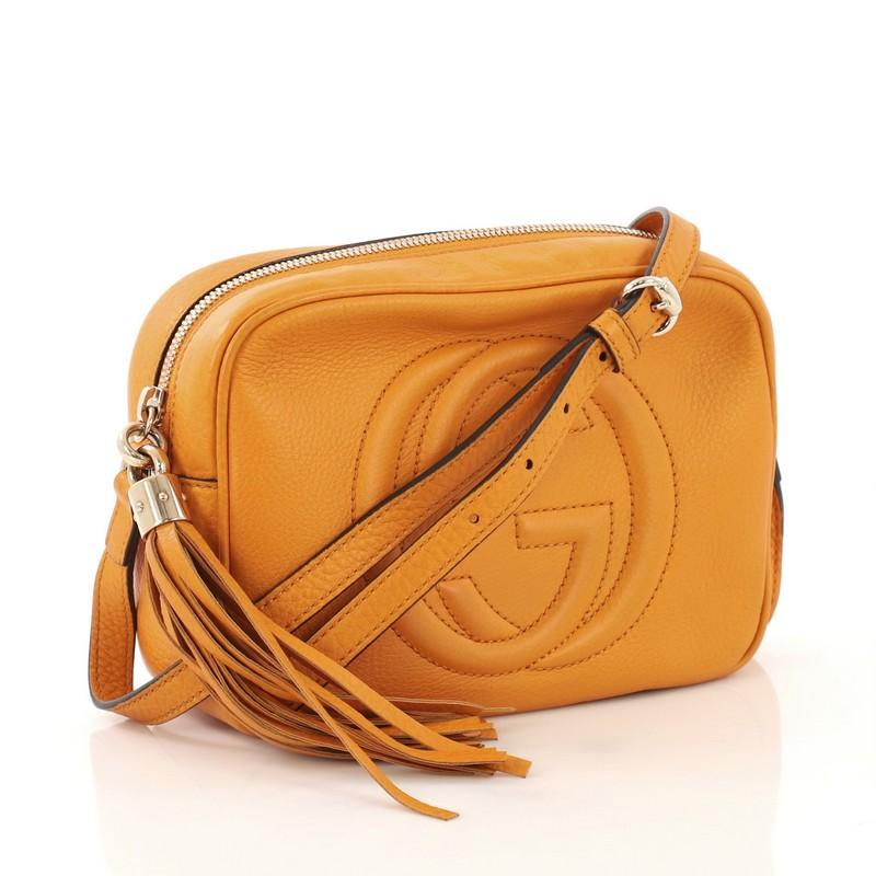 This Gucci Soho Disco Crossbody Bag Leather Small, crafted in orange leather, features an adjustable leather strap, tassel zip pull, and gold-tone hardware. Its zip closure opens to a beige fabric interior with slip pockets. 

Estimated Retail