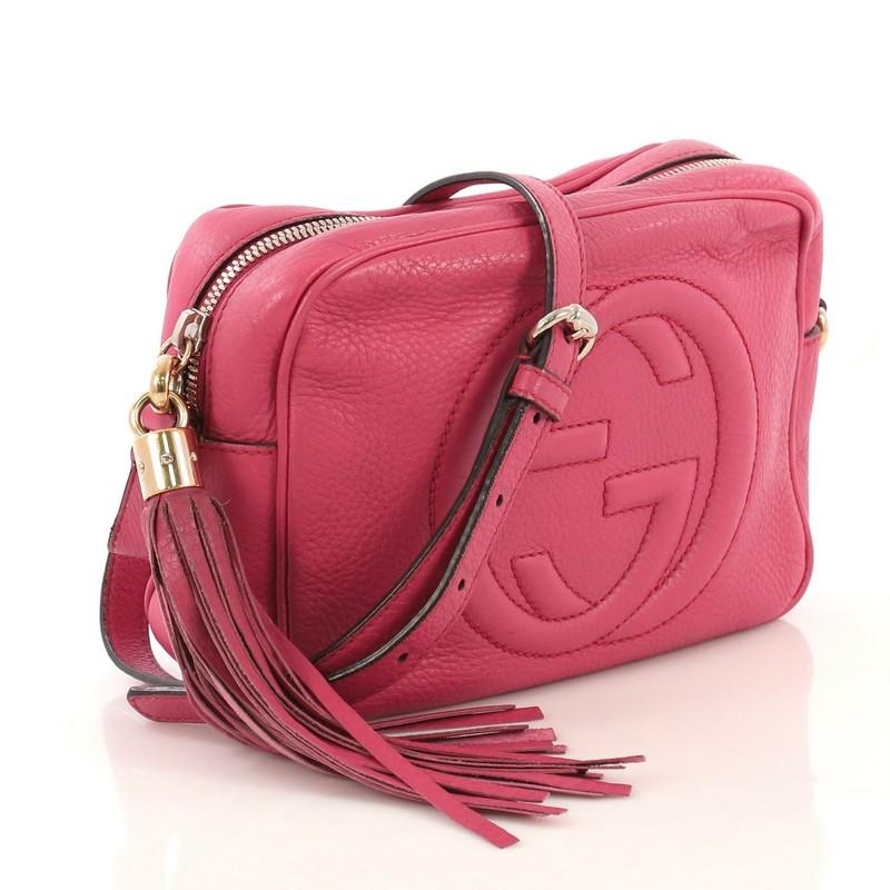 This Gucci Soho Disco Crossbody Bag Leather Small, crafted in pink leather, features an adjustable leather strap, tassel zip pull, and gold-tone hardware. Its zip closure opens to a neutral fabric interior with slip pockets. 

Estimated Retail