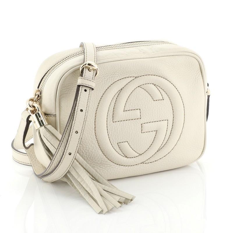 This Gucci Soho Disco Crossbody Bag Leather Small, crafted in white leather, features an adjustable leather strap, tassel zip pull, and gold-tone hardware. Its zip closure opens to a neutral fabric interior with slip pockets. 

Estimated Retail