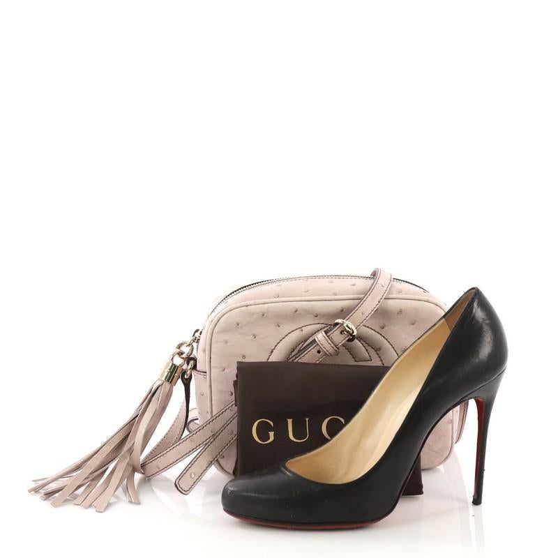 This Gucci Soho Disco Crossbody Bag Ostrich Small, crafted in light pink ostrich, features an adjustable leather strap and gold-tone hardware. Its zip closure opens to a beige canvas interior with slip pockets. **Note: Shoe photographed is used as a