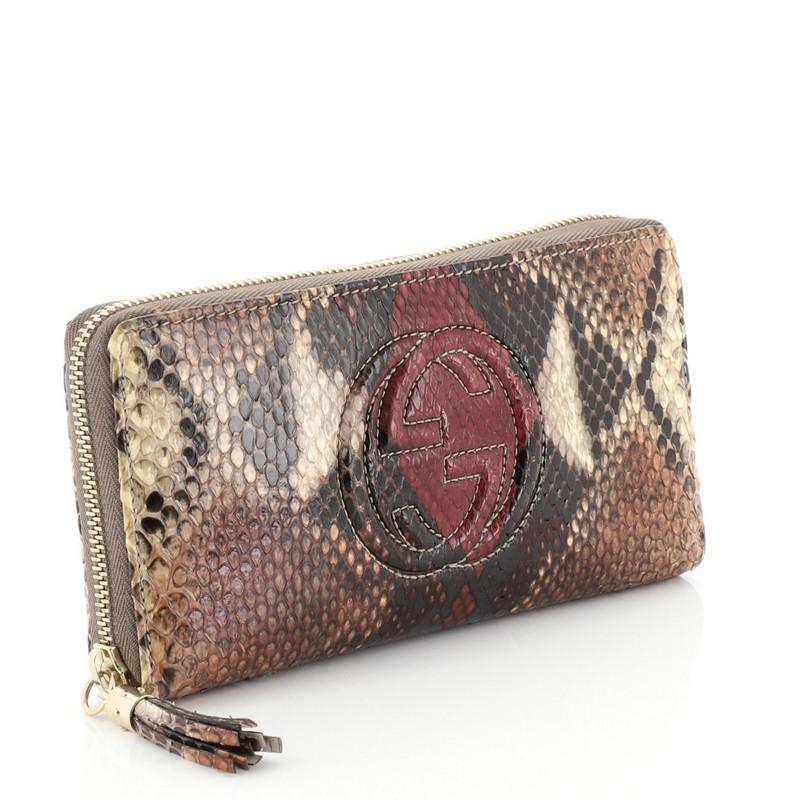 This Gucci Soho Zip Around Wallet Python, crafted in genuine brown multicolor python, features GG logo at front and gold-tone hardware. Its zip-around closure opens to a neutral leather interior with multiple card slots, center zip pocket and slip