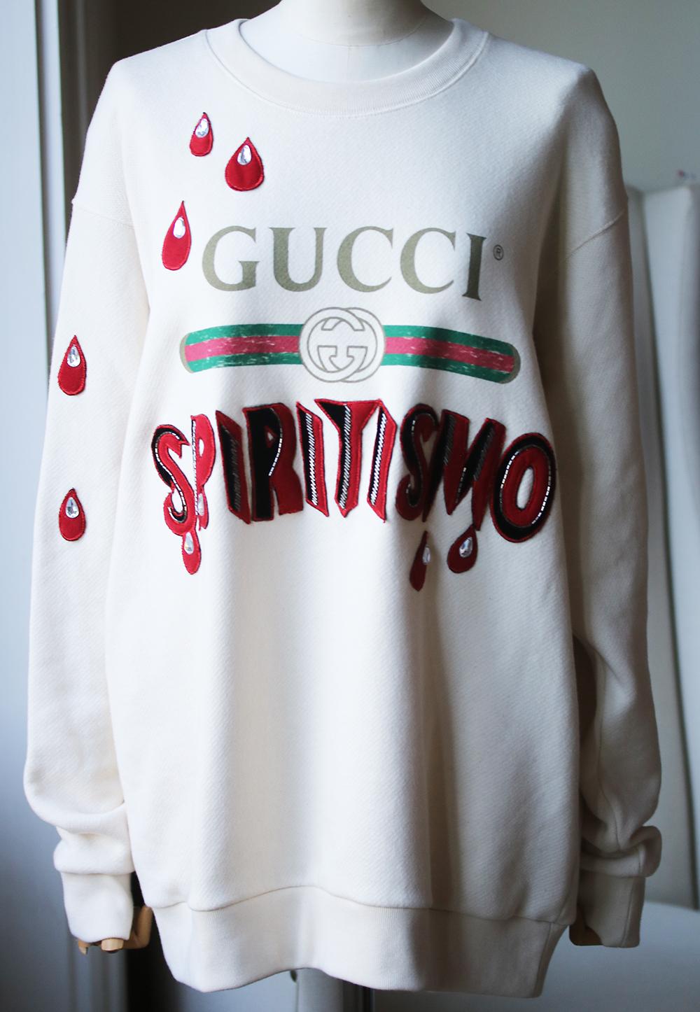 This cream and red Gucci Spiritismo cotton sweatshirt showcases a crewneck, long raglan sleeves, logo-print at the chest, embellished 'spiritismo' patch, embellished drop motif appliqués, and ribbed trims. Crafted by experts in Italy, this 100%