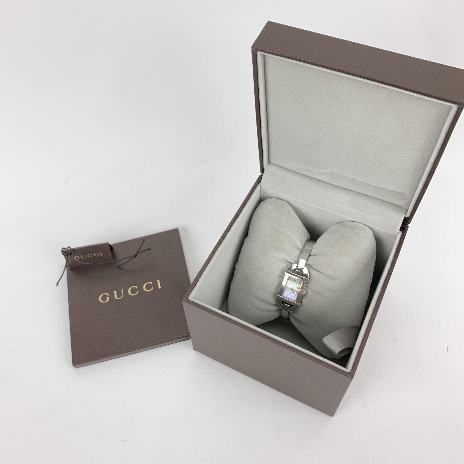 Gucci stainless steel ladies wrist watch. Model 6800 L. Stainless steel case. Quartz movement. Water Resistant (up to 3 ATM). White dial with monogram pattern. Swiss Made. Gucci written on face, clasp & reverse. White leather bangle bracelet strap.