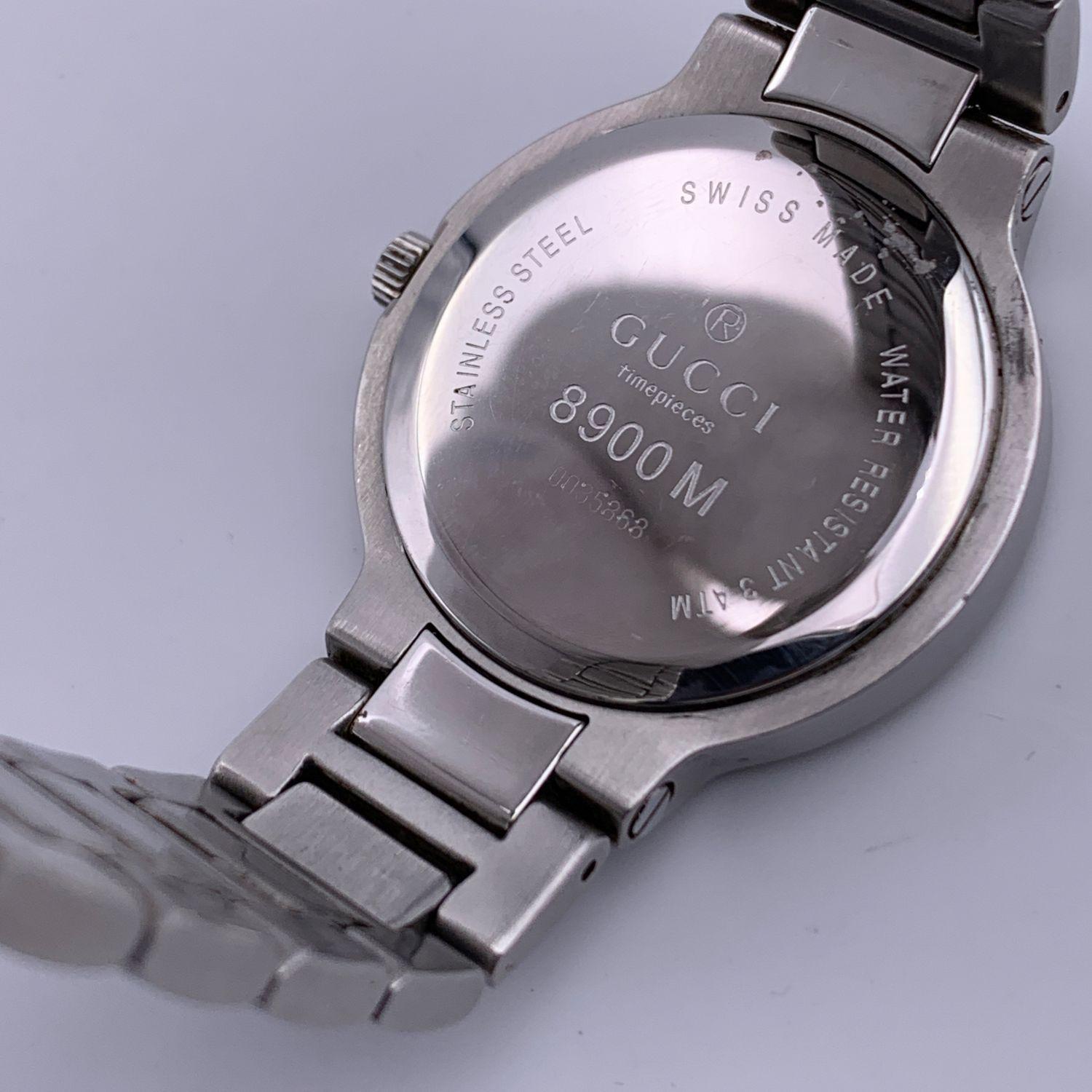 Gucci stainless steel wrist watch, mod. 8900 M. Stainless steel case. White Dial. Date at 6 o'clock. Sapphire crystal. Swiss Made Quartz movement. Gucci written on face. Arabic numbers. Water Resistant to 3atm. Deployant Clasp. Swiss Made. Will fit