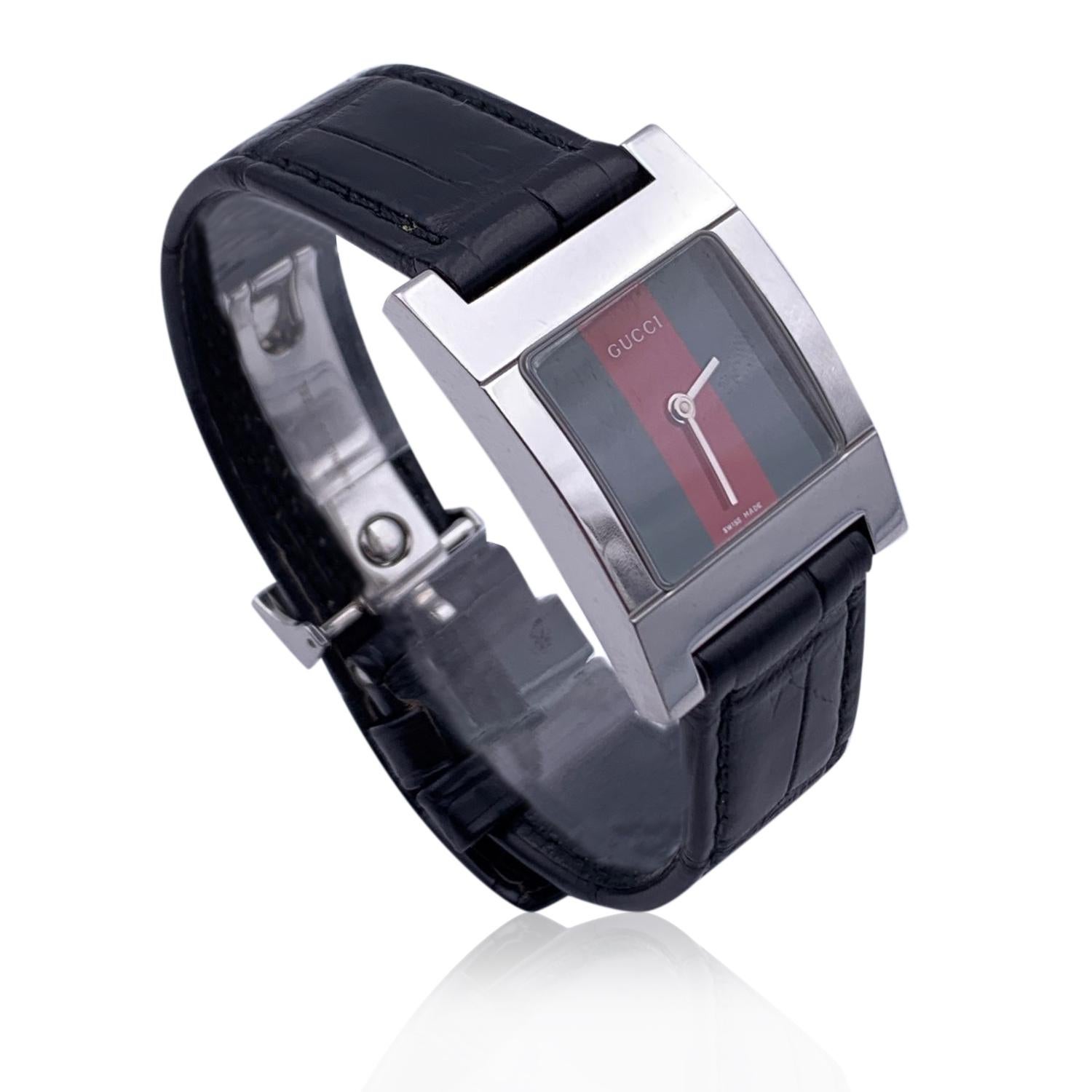Gucci silver tone stainless steel wrist watch, mod. 7700 L. Green/Red/Green Striped Dial. Date at 3 o'clock. Sapphire crystal. Swiss Made Quartz movement. Gucci written on face. Water Resistant to 3atm. Black leather strap with deployant clasp.