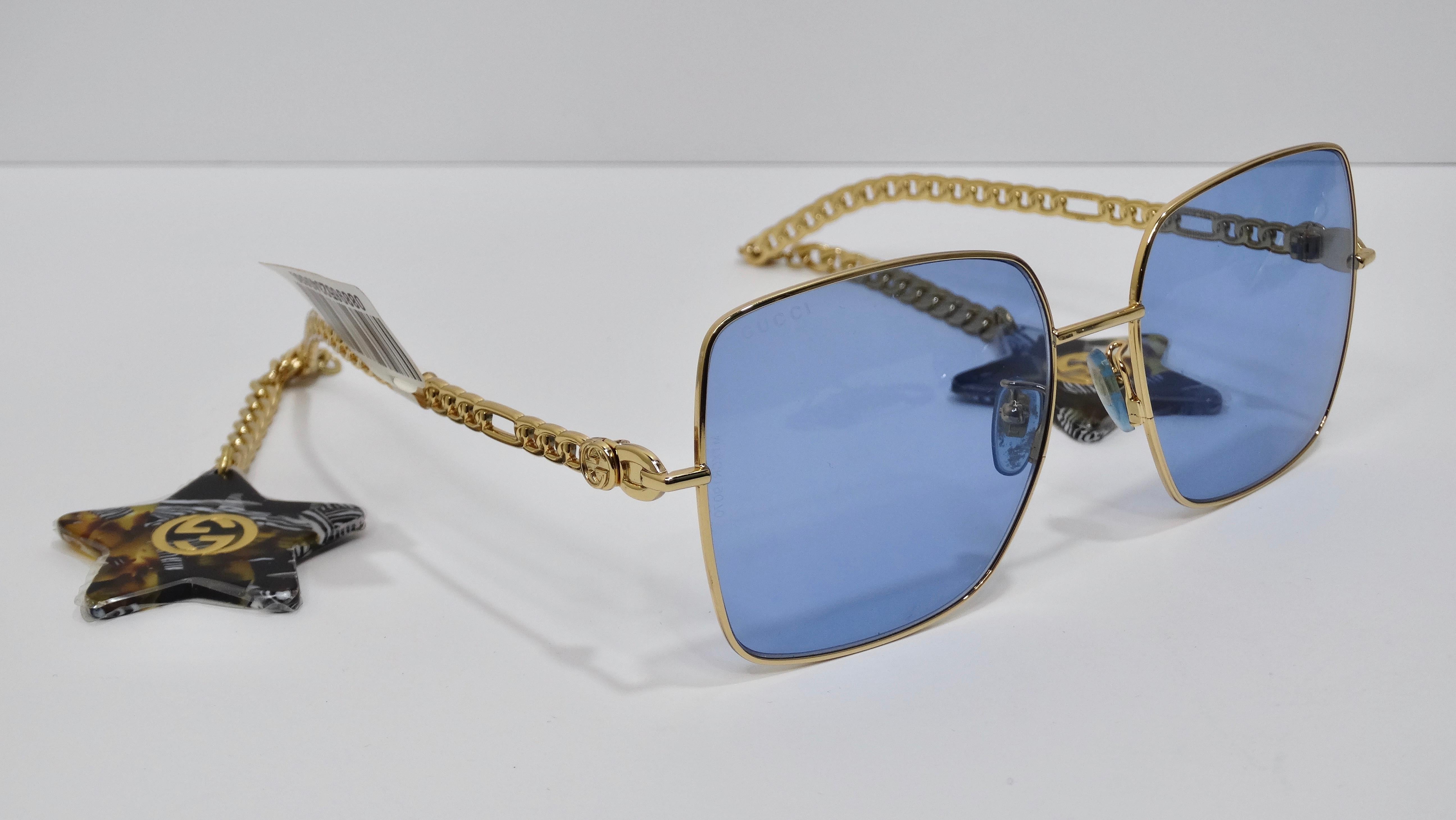 Ces lunettes de soleil sont pour les audacieux de la mode ! De la maison emblématique de Gucci, elles créent une monture dorée surdimensionnée avec des verres bleus. La tempe est pleine de détails, avec un motif de chaîne et une chaîne pendante avec