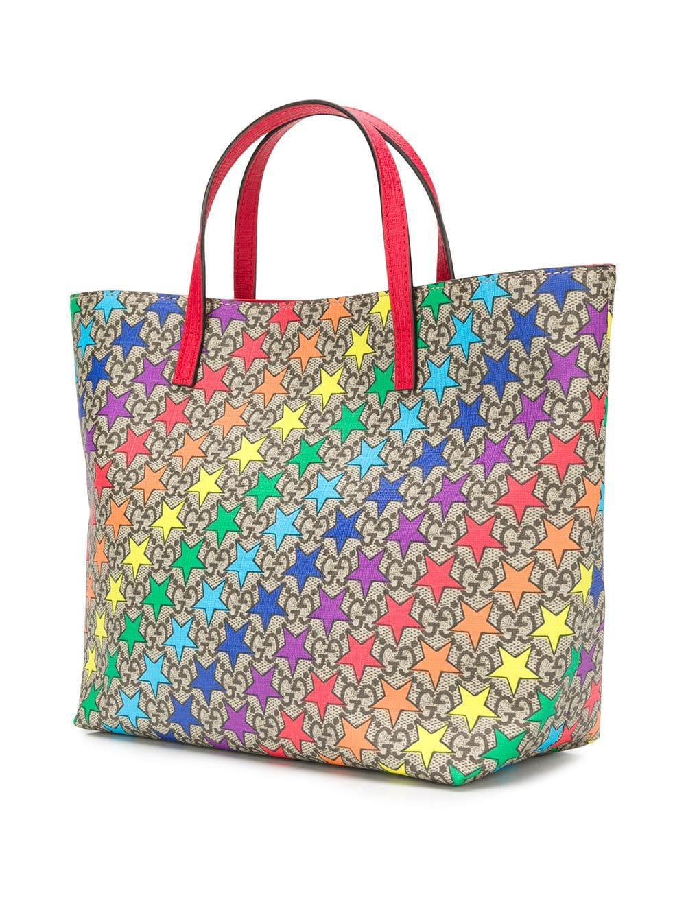 Coordinated in tones of beige, brown and ivory, this classic canvas mini tote bag by Gucci displays a myriad of coloured stars overlapping their signature monogram all-over print for an added flourish of femininity. The bag features round top