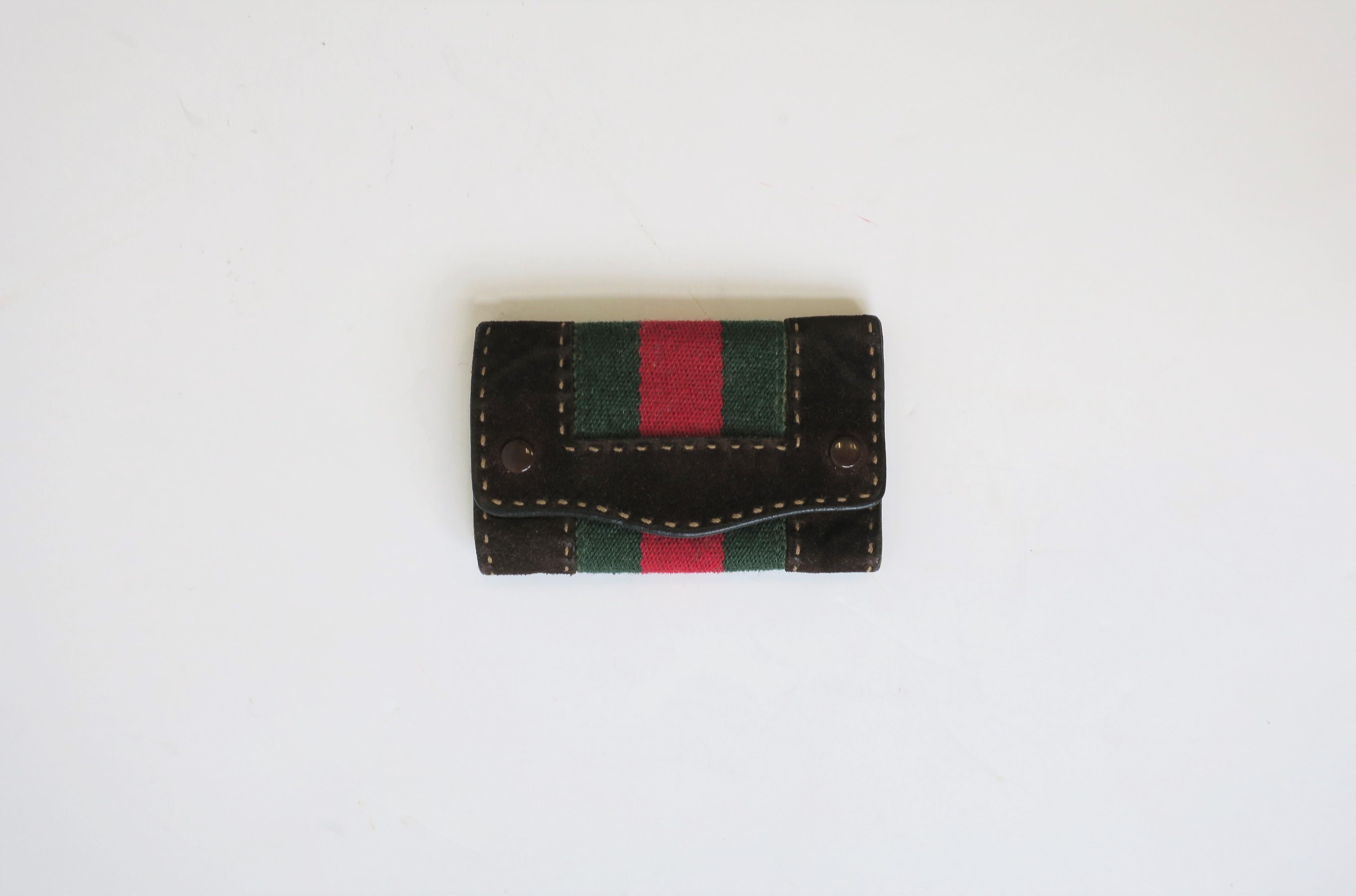 A vintage Gucci dark brown leather and suede key chain holder case with iconic red and green racing stripe from this luxury design house, circa late-20th century, Italy. Case is suede and canvas on the outside, leather on the inside, and folds