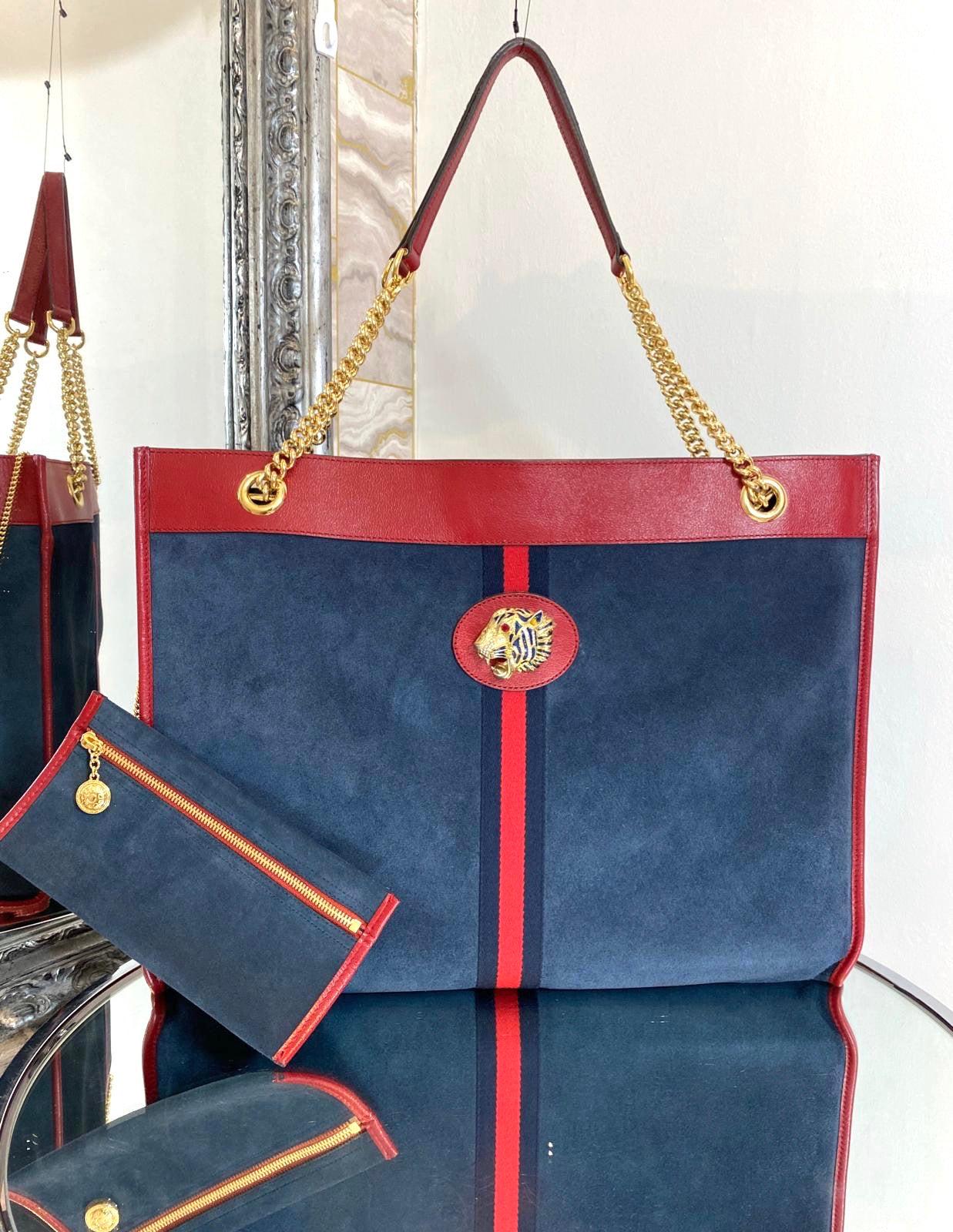 Gucci Suede Rajah Large Shopper Bag

Dark blue suede tote bag trimmed in red leather.  Enhanced by the blue and red Web inlaid onto the front. Bright red leather trim and shiny gold hardware. Stunning jewelled enamelled tiger head with crystals.