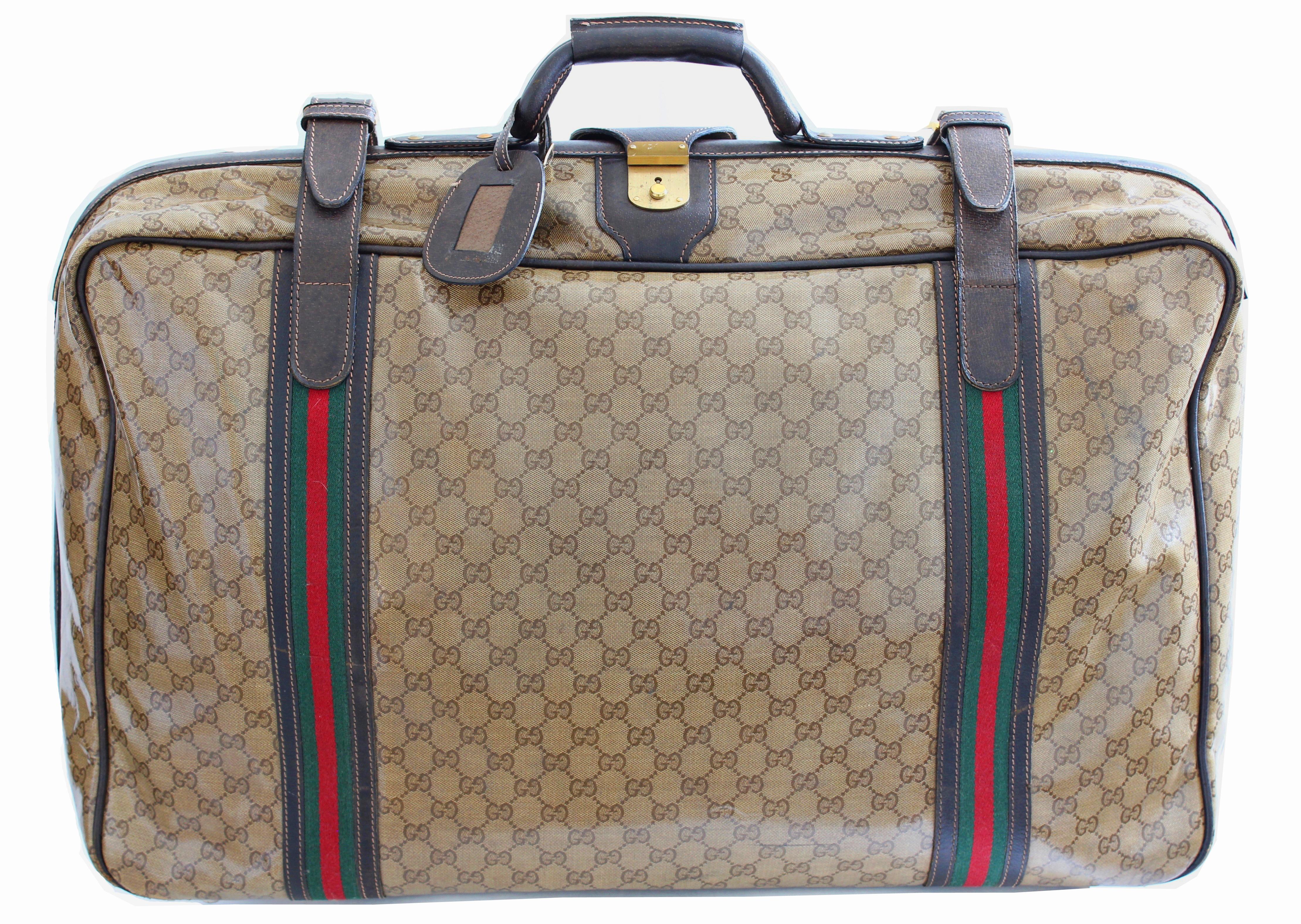 Travel in style with this classic Gucci soft side suitcase, most likely made in the late 70s.  Made from their coated canvas with GG logos, it's trimmed in brown leather and fastens with two leather straps with webbing, two chunky brass zippers and