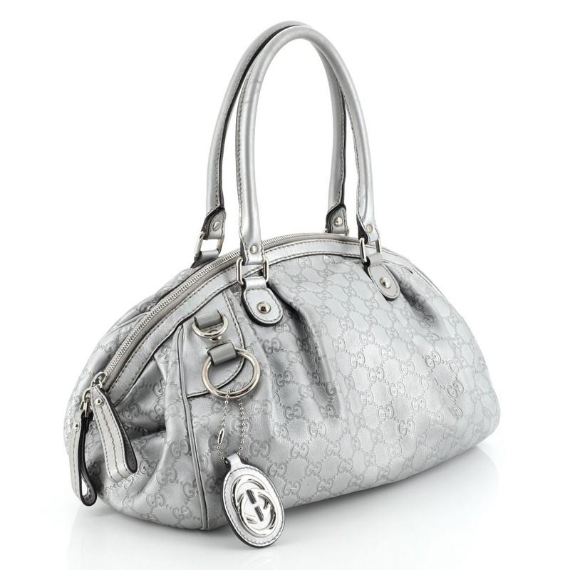 This Gucci Sukey Convertible Boston Bag Guccissima Leather, crafted in metallic silver guccissima leather, features dual rolled handles and silver-tone hardware. Its two-way zip closure opens to a neutral fabric interior with side zip pocket.