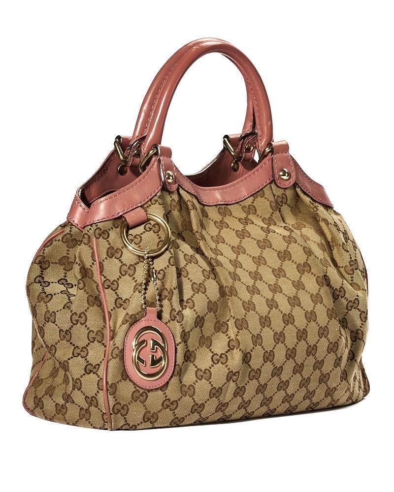 Borsa firmata Gucci, modello sukey nella misura small, realizzata in tela nella classica fantasia GG Supreme con inserti in pelle rosa e hardware dorato. Dotata di una chiusura calamitata, internamente rivestita in tela beige con comode tasche, la
