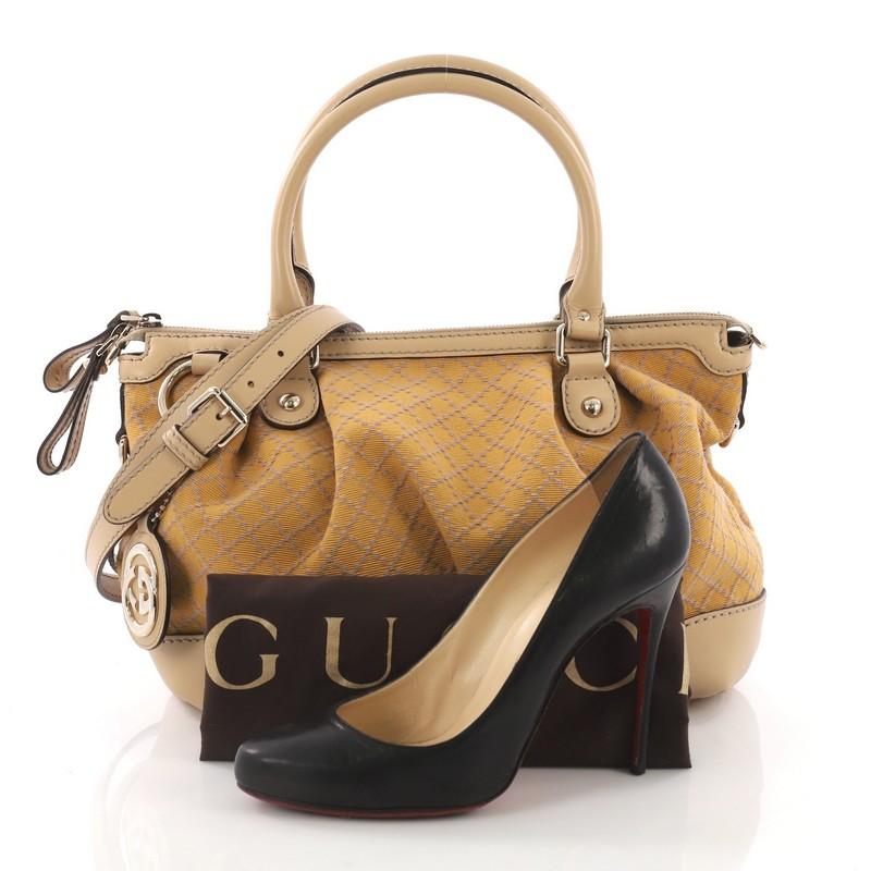 This Gucci Sukey Top Handle Satchel Diamante Canvas Medium, crafted from yellow diamante canvas with beige leather trims, features a ruched design, dual rolled handles, and gold-tone hardware. Its two-way zip closure opens to a beige fabric interior