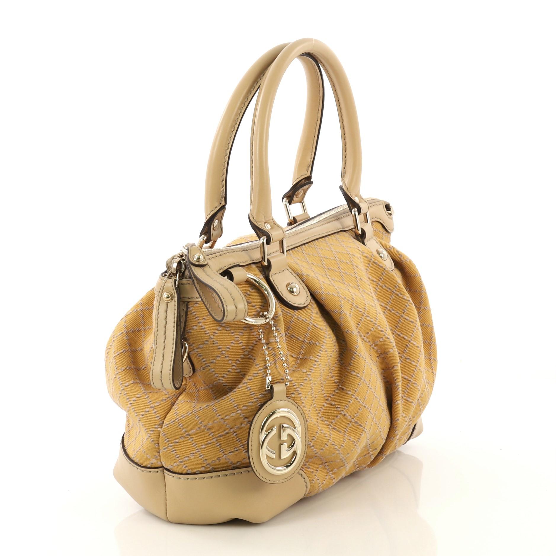 This Gucci Sukey Top Handle Satchel Diamante Canvas Medium, crafted from yellow diamante canvas, features dual rolled handles, leather trim, and gold-tone hardware. Its two-way zip closure opens to a neutral fabric interior with side zip and slip