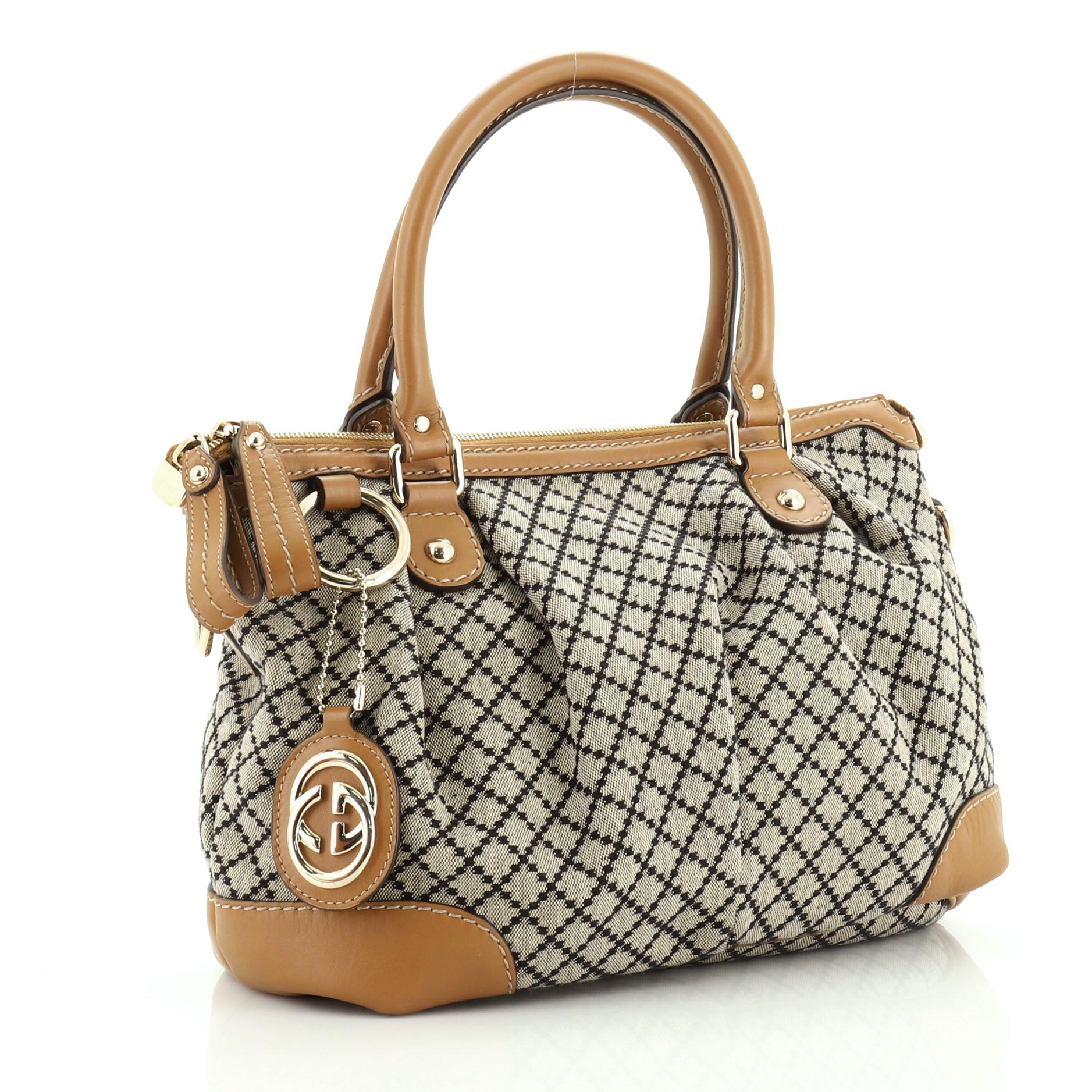 This Gucci Sukey Top Handle Satchel Diamante Canvas Medium, crafted from brown diamante canvas, features dual rolled handles, leather trim, and gold-tone hardware. Its two-way zip closure opens to a neutral fabric interior with side zip and slip
