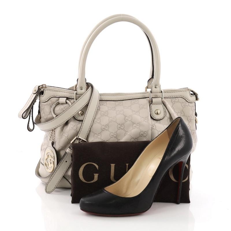 This Gucci Sukey Top Handle Satchel Guccissima Leather Medium, crafted in beige guccissima leather, features dual rolled leather handles, pleated silhouette, and gold-tone hardware. Its zip closure opens to a beige fabric interior with side zip and