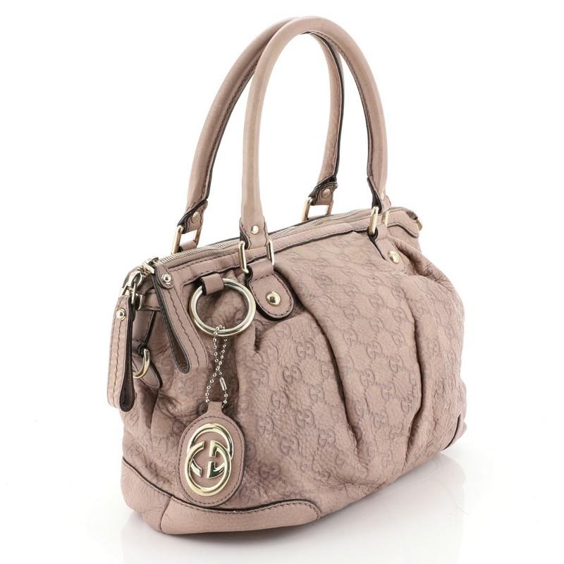 This Gucci Sukey Top Handle Satchel Guccissima Leather Medium, crafted in pink guccissima leather, features dual rolled leather handles, pleated silhouette, and gold-tone hardware. Its zip closure opens to a neutral fabric interior with side zip and