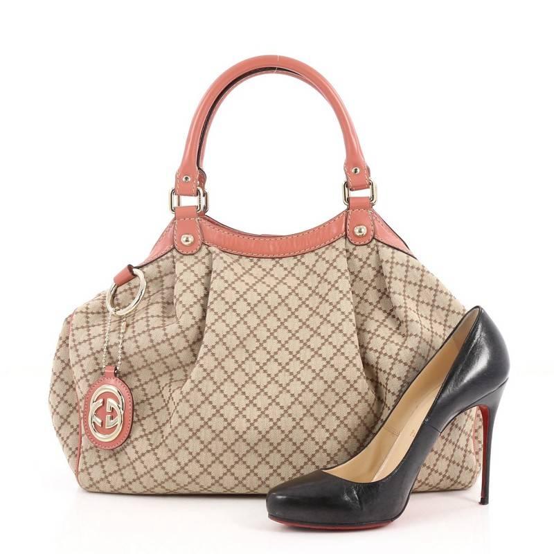 This authentic Gucci Sukey Tote Diamante Canvas Medium is sophisticated and chic perfect for casual excursions. Crafted in light brown diamante canvas and pink leather trims, this soft bag features dual-rolled handles, pleated details, Gucci logo