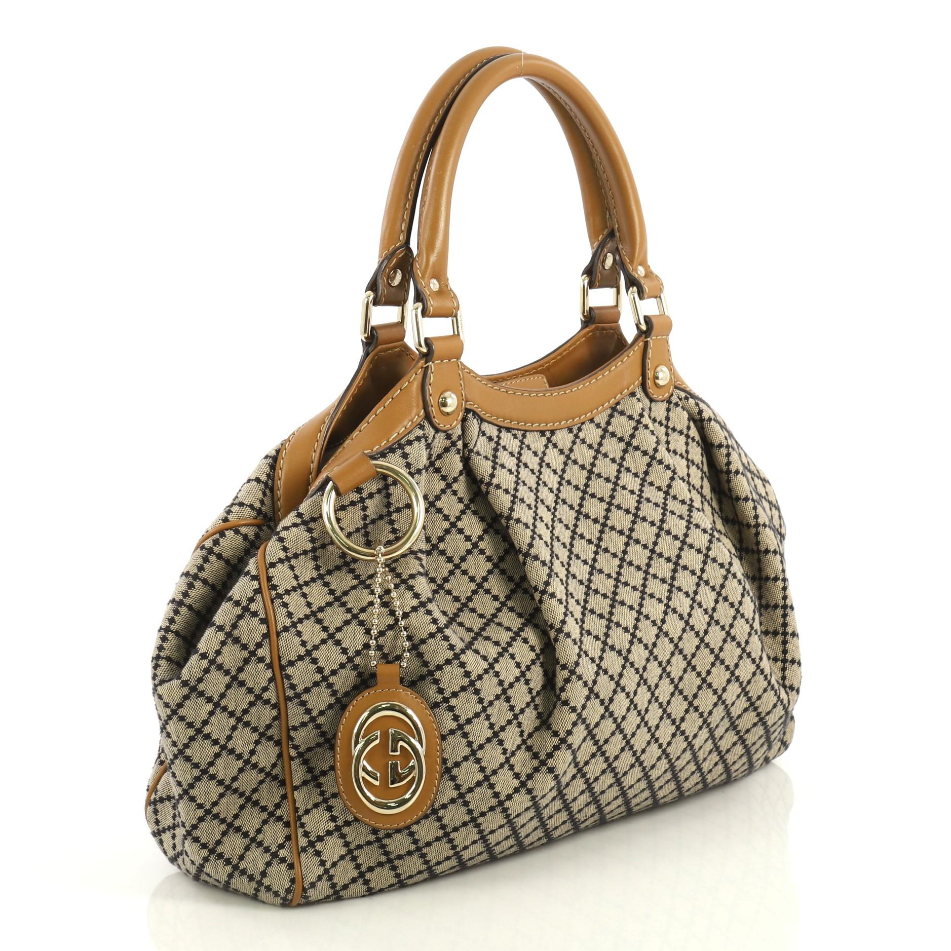 This Gucci Sukey Tote Diamante Coated Canvas Medium, crafted in brown diamante coated canvas, features dual rolled handles, pleated details, side snap buttons and gold-tone hardware. Its magnetic snap closure opens to a neutral fabric interior with