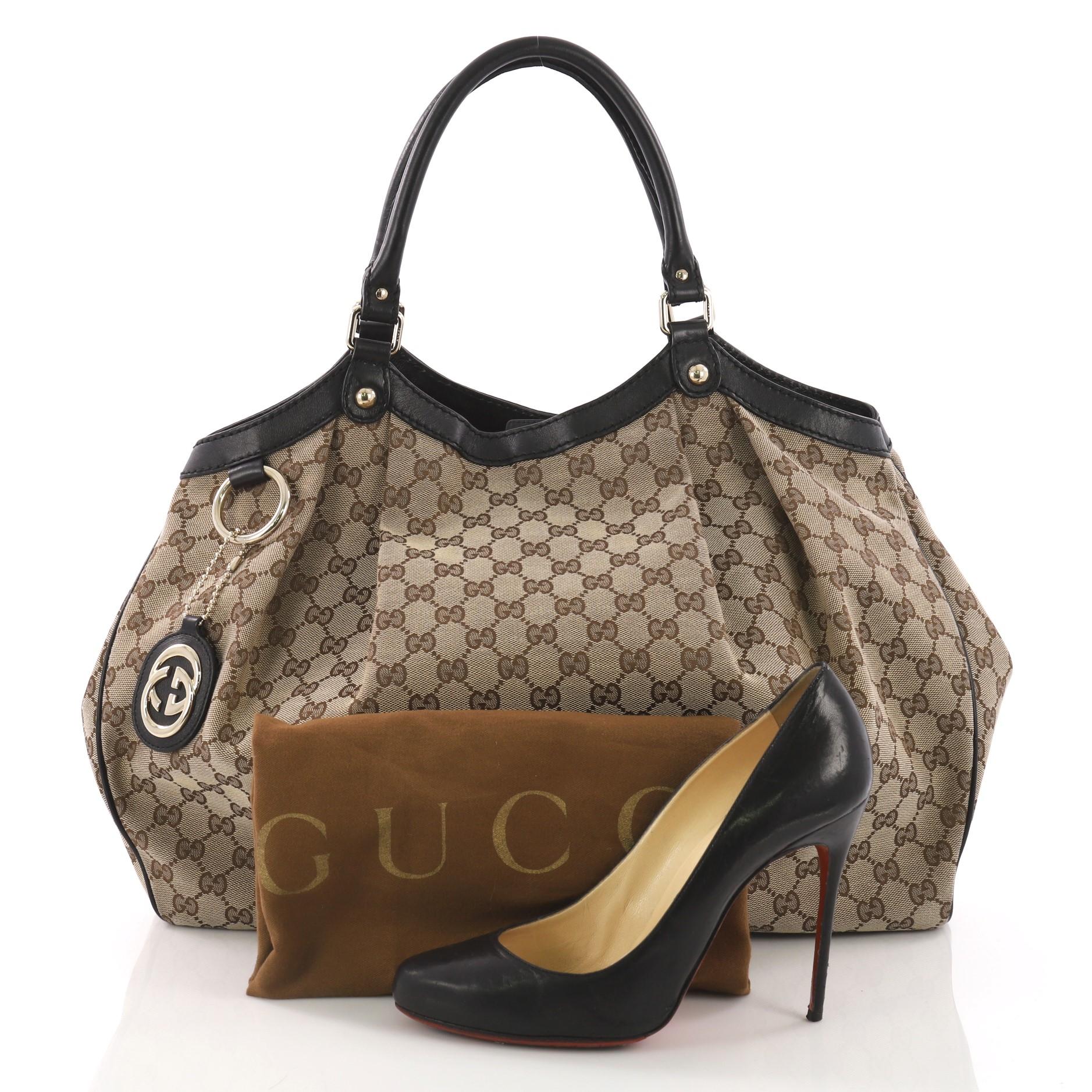 This Gucci Sukey Tote GG Canvas Large, crafted from brown GG canvas with leather trims, features dual rolled leather handles, ruched silhouette, and gold-tone hardware. Its side snap and magnetic closures opens to a brown fabric interior with zip