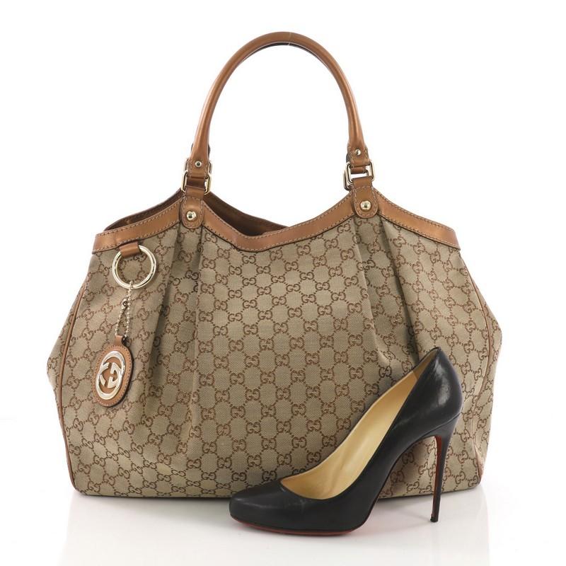 This Gucci Sukey Tote GG Canvas Large, crafted from brown GG canvas, features dual rolled leather handles, a ruched silhouette, and gold-tone hardware. Its side snap and magnetic closures opens to a brown fabric interior with zip pocket. **Note: