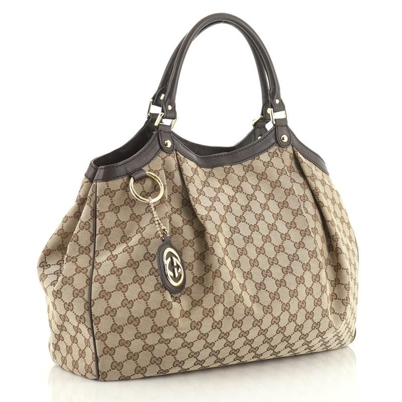 This Gucci Sukey Tote GG Canvas Large, crafted from brown GG canvas, features dual rolled leather handles, leather trim, and gold-tone hardware. Its magnetic snap closure opens to a brown fabric interior with zip pocket. 
Condition: Great. Wear on