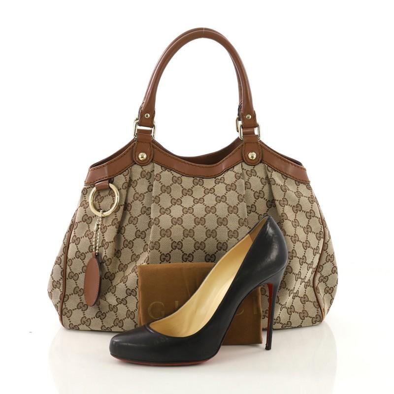 This Gucci Sukey Tote GG Canvas Medium, crafted from light brown GG canvas and brown leather, features dual rolled leather handles, ruched silhouette, and gold-tone hardware. Its side snap and magnetic snap closures open to a brown fabric interior