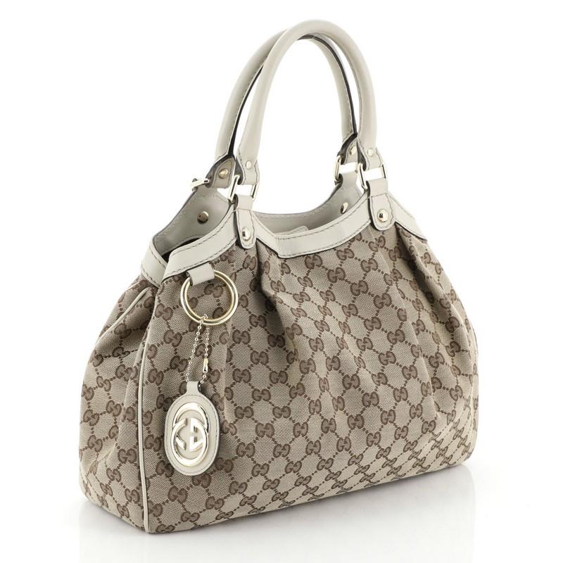 This Gucci Sukey Tote GG Canvas Medium, crafted from brown GG canvas, features dual rolled leather handles, leather trim, and gold-tone hardware. Its magnetic snap closure opens to a brown fabric interior with side zip pocket. 

Estimated Retail