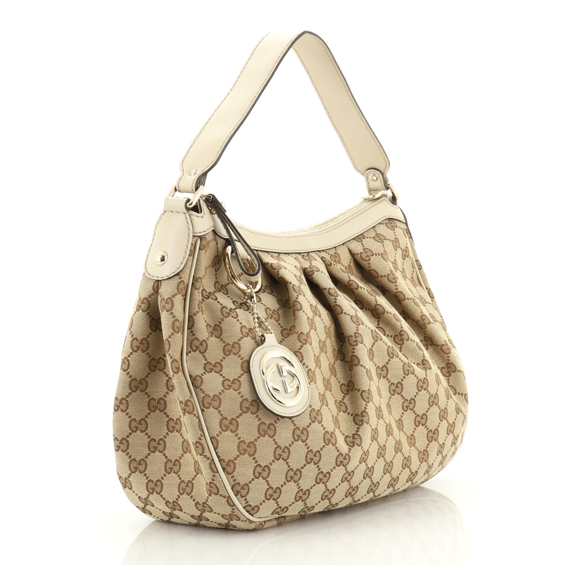 This Gucci Sukey Tote GG Canvas Medium, crafted from brown GG canvas, features dual rolled leather handles, leather trim, and gold-tone hardware. Its magnetic snap closure opens to a neutral fabric interior with side zip pocket.

Estimated Retail