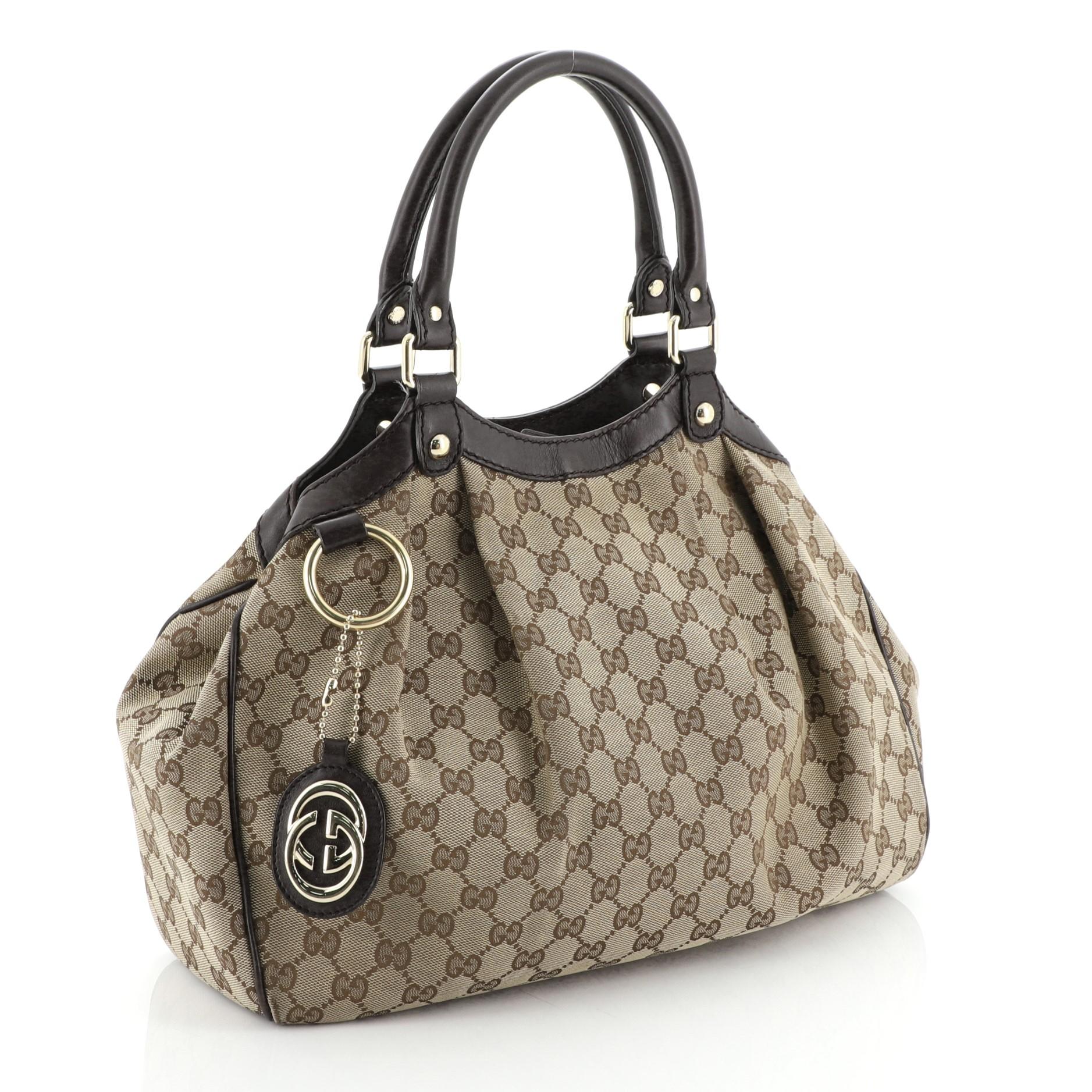 This Gucci Sukey Tote GG Canvas Medium, crafted from neutral GG monogram canvas, features dual rolled leather handles, leather trim, and gold-tone hardware. Its magnetic snap closure opens to a brown fabric interior with side zip pocket. 

Estimated