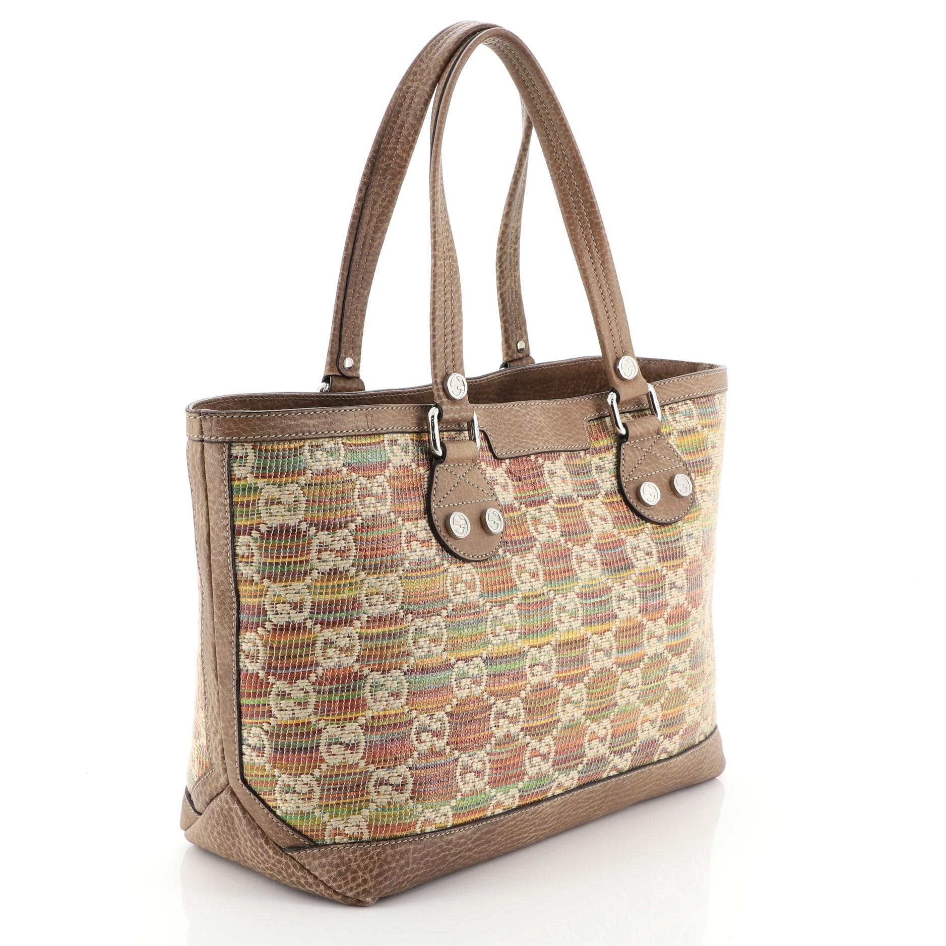 This Gucci Sunset Tote Straw Libeccio GG Canvas Small, crafted in multicolor red, brown straw Libeccio GG canvas, features dual leather handles with interlocking GG studs, brown leather trims and silver-tone hardware. Its hook closure opens to a