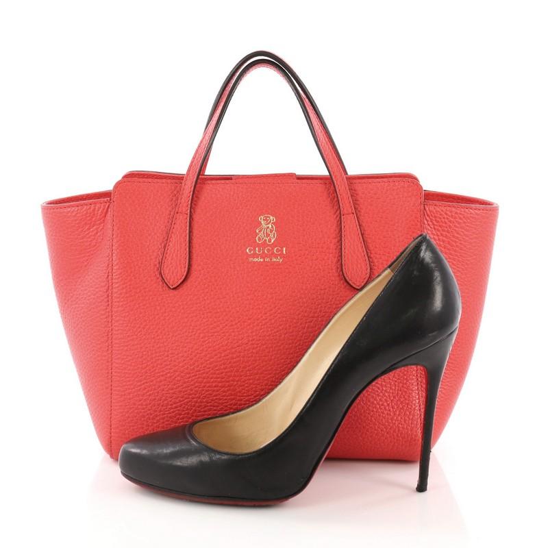 This Gucci Swing Tote Leather Small, crafted in pink leather, features dual slim handles, Gucci stamped logo at the front, and an expanded wing silhouette. Its hidden magnetic snap closure opens to a beige fabric interior with slip pocket. **Note: