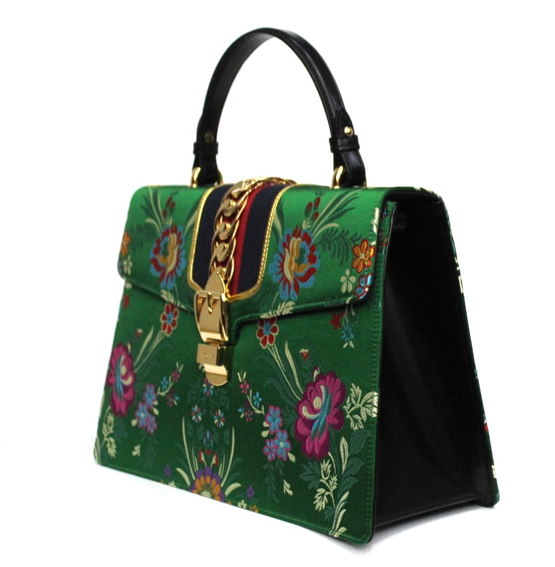 Sylvie handbag with Web detail in nylon inserted under the fabric and decorated with buckle and gold chain. The metal buckle closure from the Maison's archives is wisely combined with the striped Web detail. New model in jacquard fabric with floral