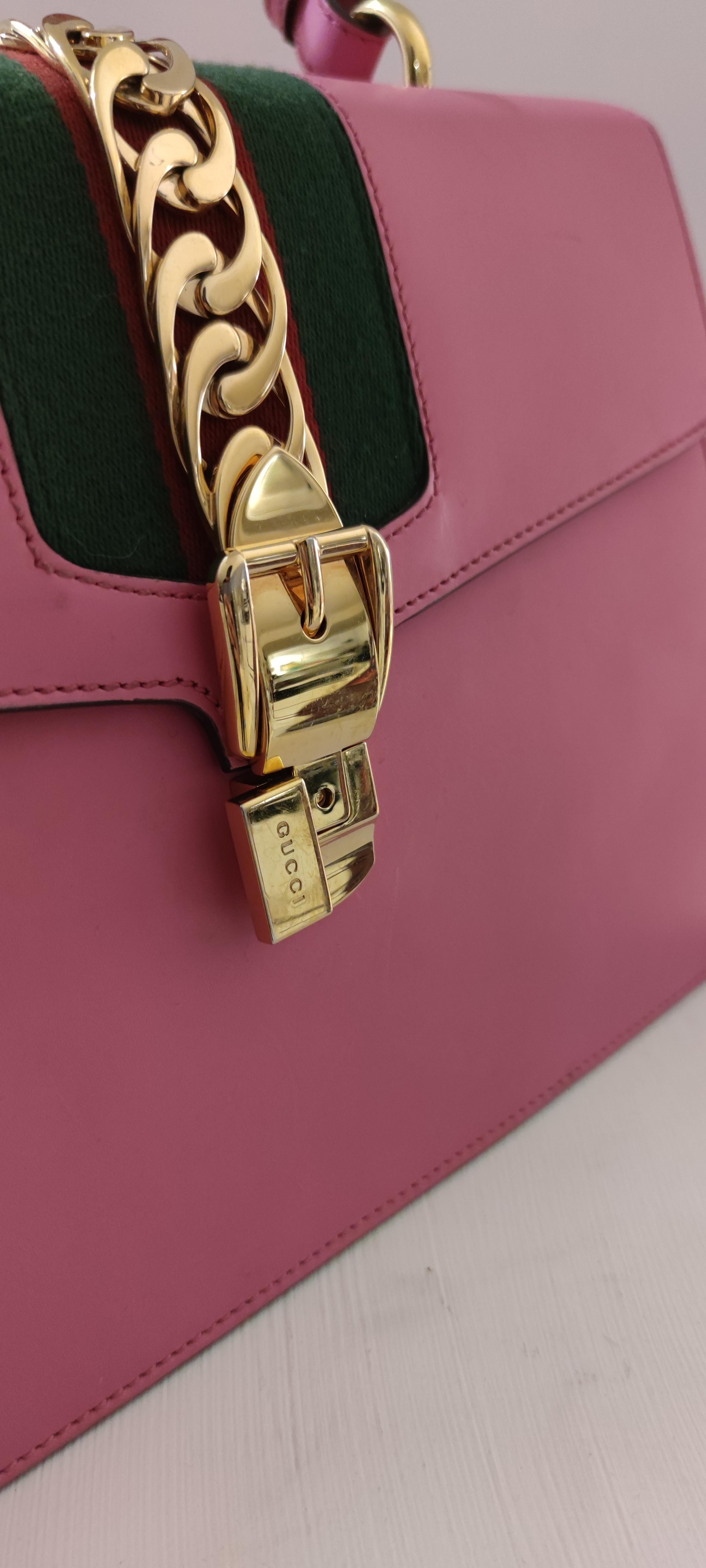 Gucci Sylvie bag in a beautiful top handle shape with Gucci nylon Web embedded under the leather and decorated with a gold chain and buckle. Made in smooth, classic leather.

Pink leather
Gold-toned hardware
Green and red nylon Web detail with metal