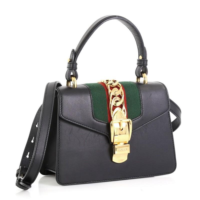 This Gucci Sylvie Top Handle Bag Leather Mini, crafted from blue leather, features a single looped leather handle, nylon web detail with curb chain, and gold-tone hardware. Its buckle closure opens to a neutral microfiber interior with side slip