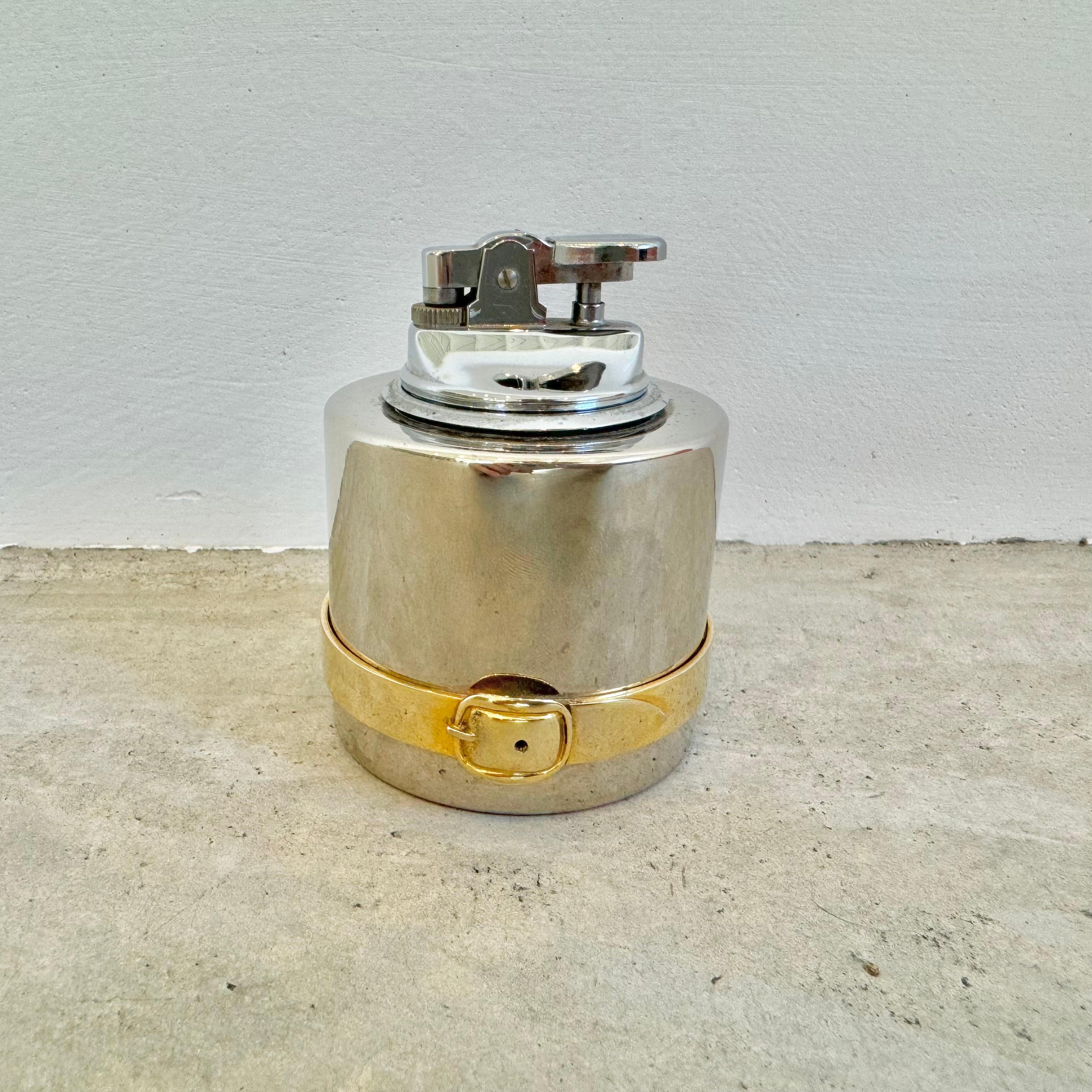Elegantes und einzigartiges Gucci Tischfeuerzeug. Ein solider Metallkörper mit einem goldfarbenen Gürtel und einer Schnalle um das untere Viertel des Feuerzeugs. Auf dem Sockel ist 