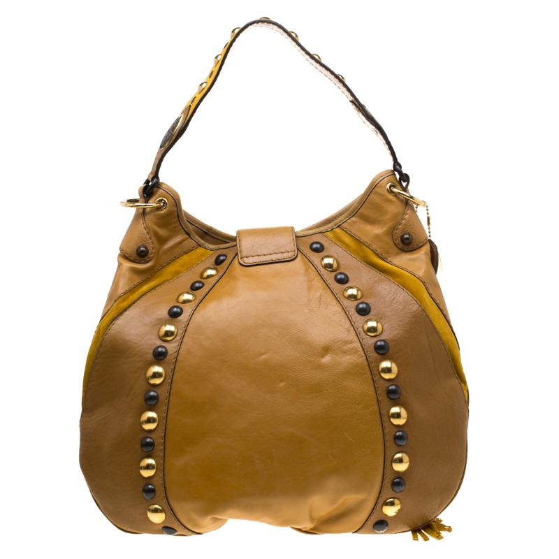 Make a standout addition to your collection by adding this Babouska hobo from Gucci. Crafted from tan leather, it is decorated with studs and fringes. Made in Italy, this hobo features a shoulder strap, single handle and emblem charms in gold-tone.