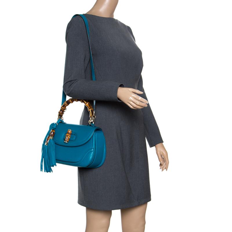 Handbags from Gucci are on every woman's wishlist. So, own this gorgeous Bamboo bag today and light up your closet! Crafted from leather, this stunning teal blue number has a bamboo turn lock on the flap that opens to a canvas lined interior. It