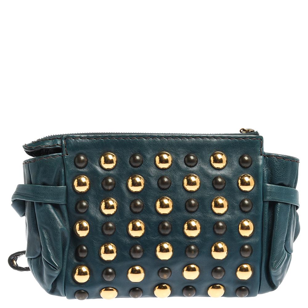 This Gucci clutch is built to suit your stylish ensembles. Crafted in Italy, it is made from quality leather and comes in a teal hue. It is complete with a Hysteria emblem as well as studs on the front and a wristlet. It has ties on the sides and a