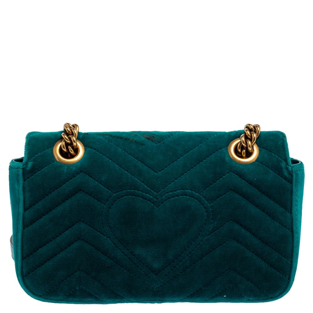 Diese tealfarbene Marmont-Tasche wurde in exquisiter Handarbeit aus Matelassesamt gefertigt und mit einem großzügigen Innenraum aus Satin und Leder ausgestattet. Auf der vorderen Klappe befindet sich ein goldfarbenes GG-Logo:: und an der mit
