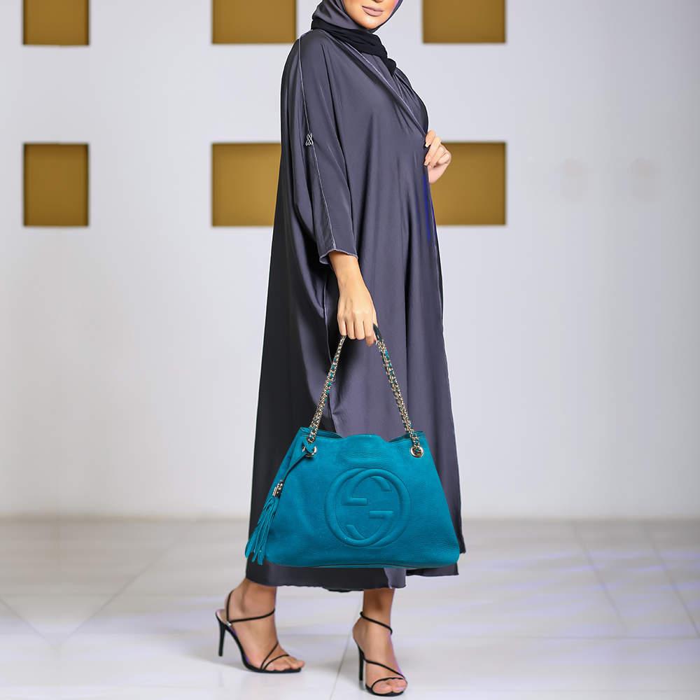 This Gucci Soho tote is defined by refined luxury and timeless elegance. Crafted from teal nubuck leather  the GG motif on the front adds a signature touch to the bag  and it is made functional with dual chain leather handles at the top. The tassel