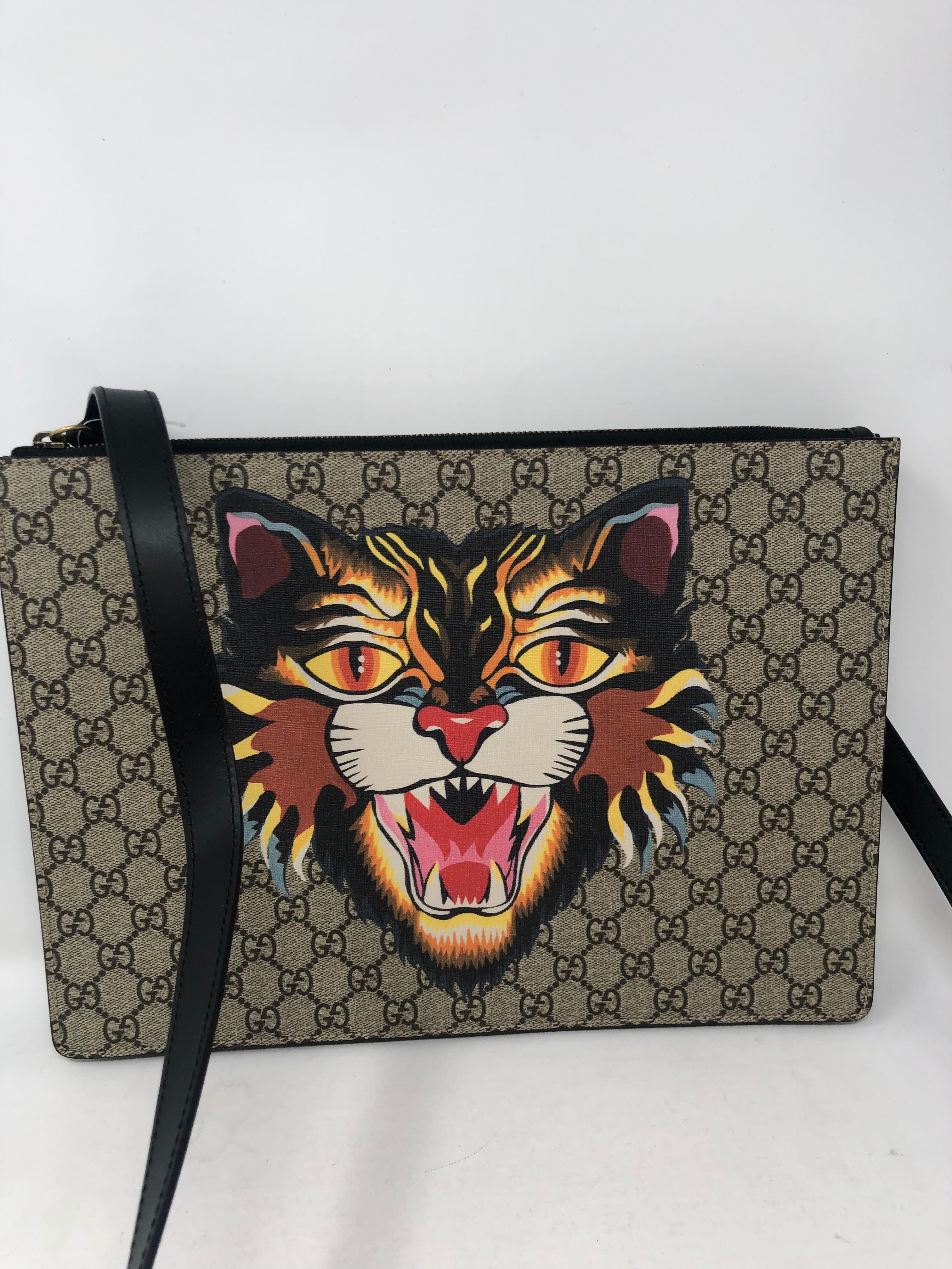 Gucci Tiger Clutch and Crossbody Bag. Gucci mono with big Tiger printed on one side. Has detachable leather strap that can taken off. Worn as a big clutch or laptop holder. New condition. Clean interior. Never used. Guaranteed authentic.